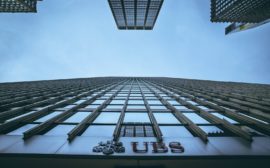 Low angle view of New York skyscrapers with UBS logo, emphasizing height and urban architecture.